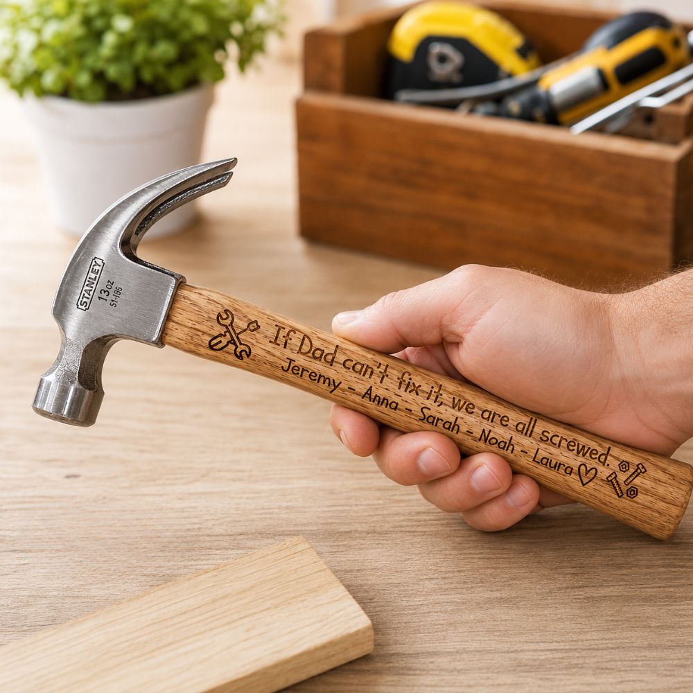 Hammer with engraved wooden handle held in a hand; reads, "If Dad can't fix it, we are all screwed" followed by family names, with tools in the background (DIY scene).